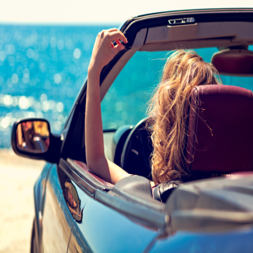 Woman parked in a convertible overlooking ocean