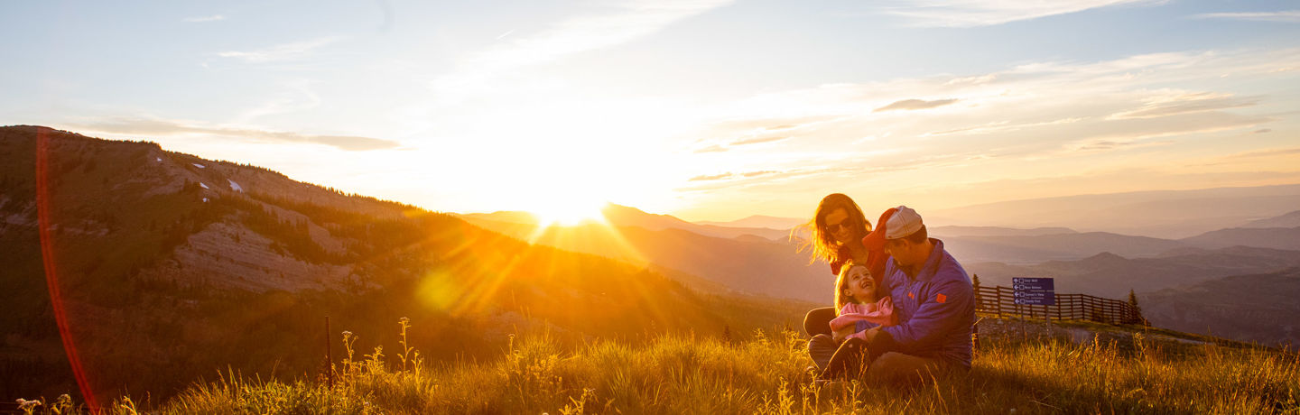 A family enjoys the summer sunset from atop Snowmass mountain