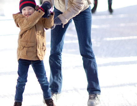 Child holding parents hand while Ice skating