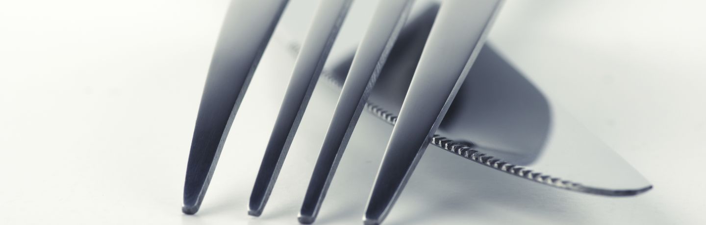 Close-up of fork and knife on white background. Soft focus, shallow DOF. Toned image.