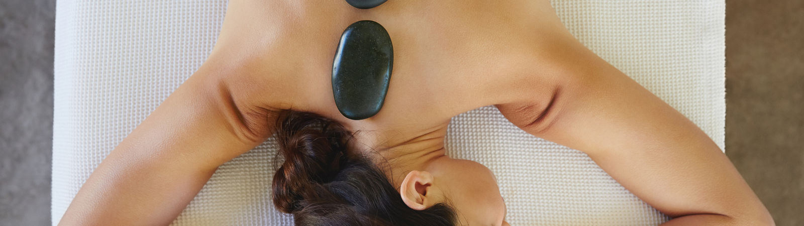 Directly above shot of relaxed young woman receiving hot stone therapy in spa
