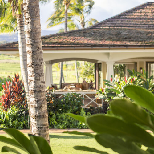 Looking through the lush foliage across the lawn to the open air seating of the Kukui'ula Club House restaurant. 