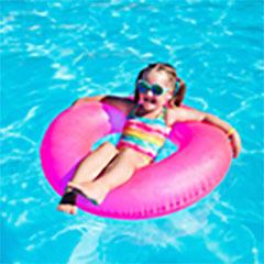 little girl on pink pool float